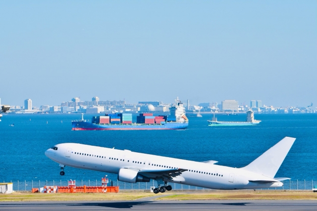 海上に浮かぶ貨物船を背景に航空機が離陸している